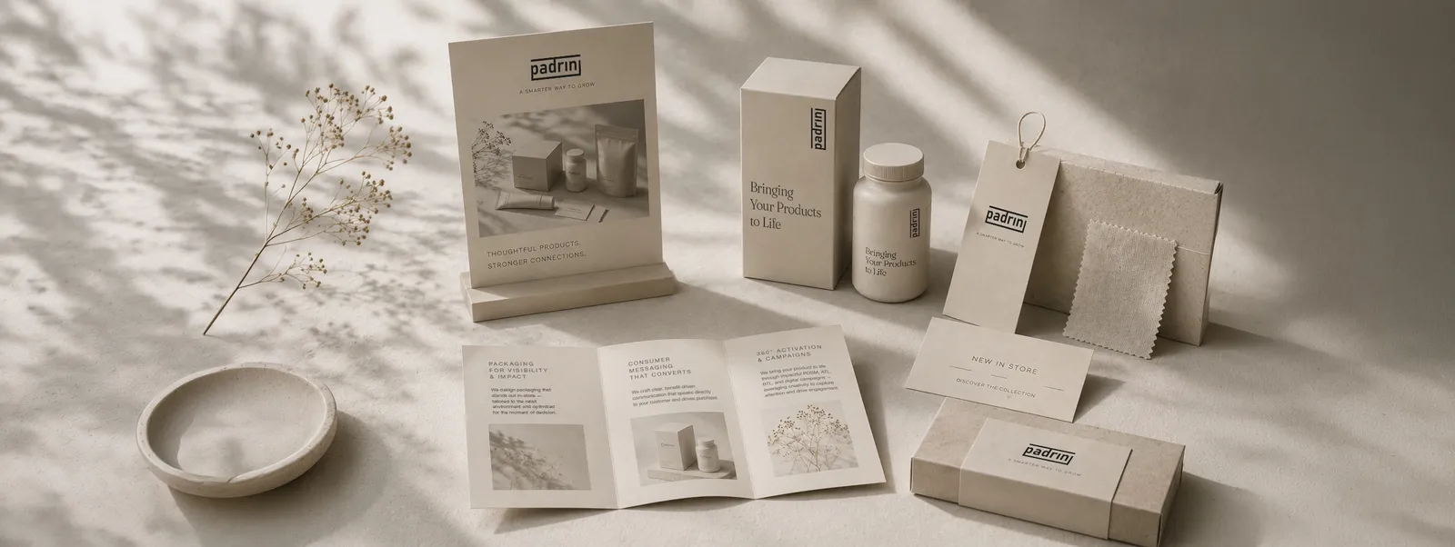 Padrini retail marketing collateral — counter display, brochure, hangtag and product packaging in soft daylight